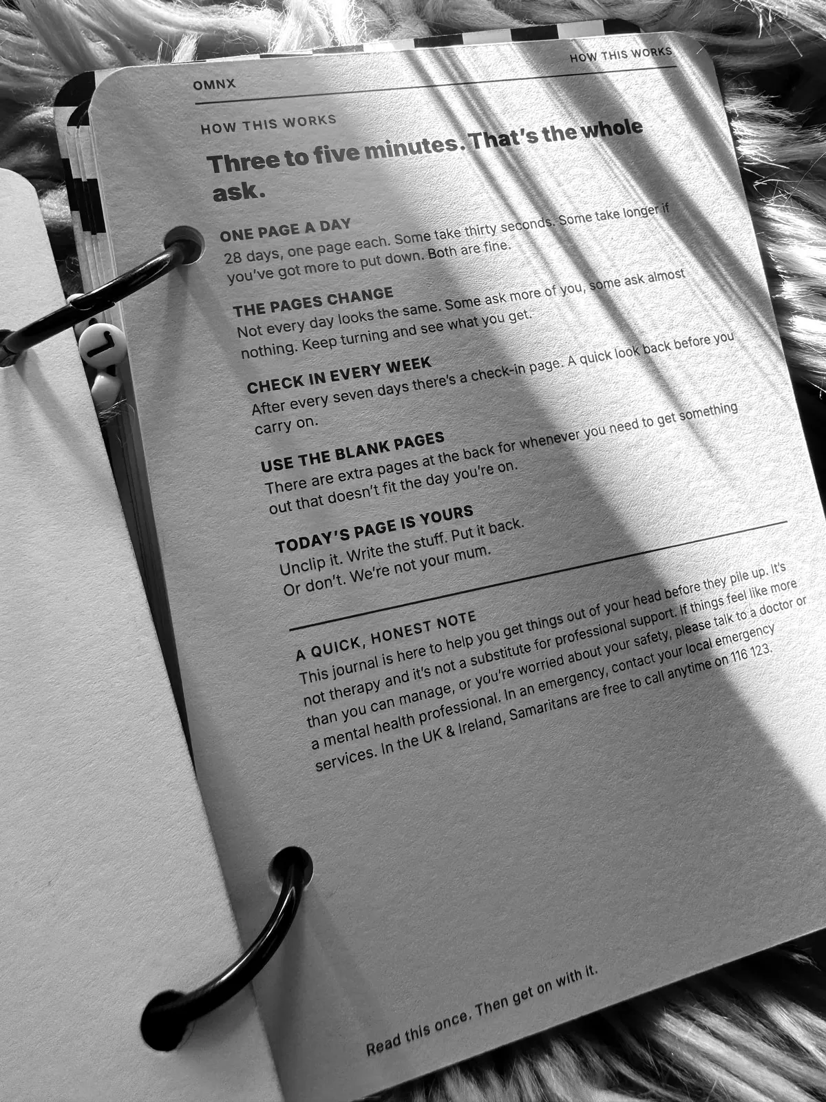 The HOW THIS WORKS page, headed Three to five minutes. That's the whole ask., explaining one page a day, a weekly check-in and the blank pages, above a short note pointing to professional support and Samaritans