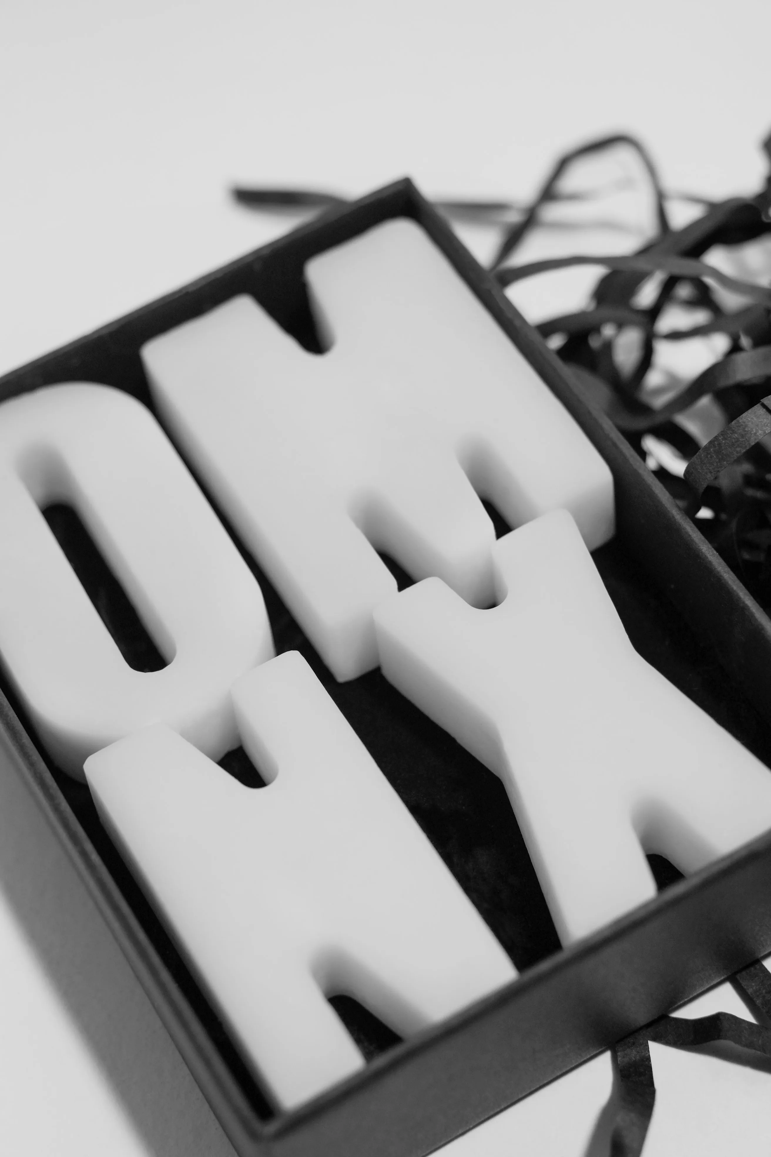 The four Pause letters close up in their tray, O, M, N and X moulded in pale wax
